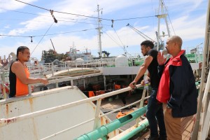 Dane Duplessis (right) and Cassiem Augustus (far right), advise a fisherman (left) at the Cape Town Port